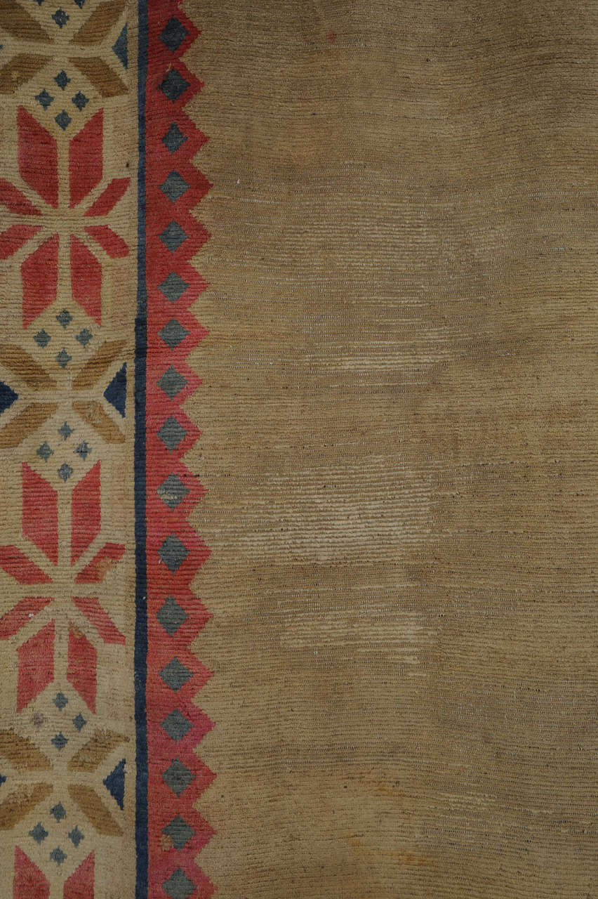 Ein einzigartiger und eleganter tibetischer Teppich im Großformat, der wahrscheinlich seinerzeit für einen besonderen Zweck in Auftrag gegeben wurde. Das neutrale, offene Feld wird von einer Reihe von Bordüren umrahmt, von denen die größte eine